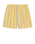 The Pop Boxer by Donni features a relaxed fit with vertical blue and white stripes on yellow cotton poplin. An elastic waistband ensures comfort, and buttons down the front add a classic touch, set against a plain white background.