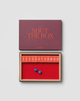Printworks Shut The Box wooden game with numbered board and two blue dice, shown with its storage box.