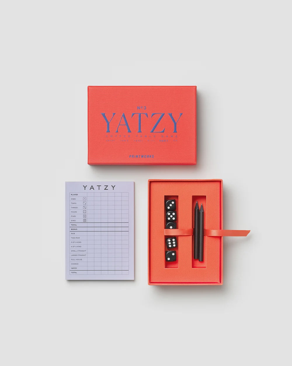 Printworks Yatzy game set in a red box, including a scorecard, five black dice, and two pencils.