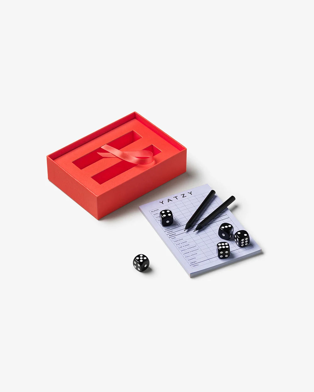 Printworks Yatzy game set in a red storage box with five black dice, two pens, and a score pad.