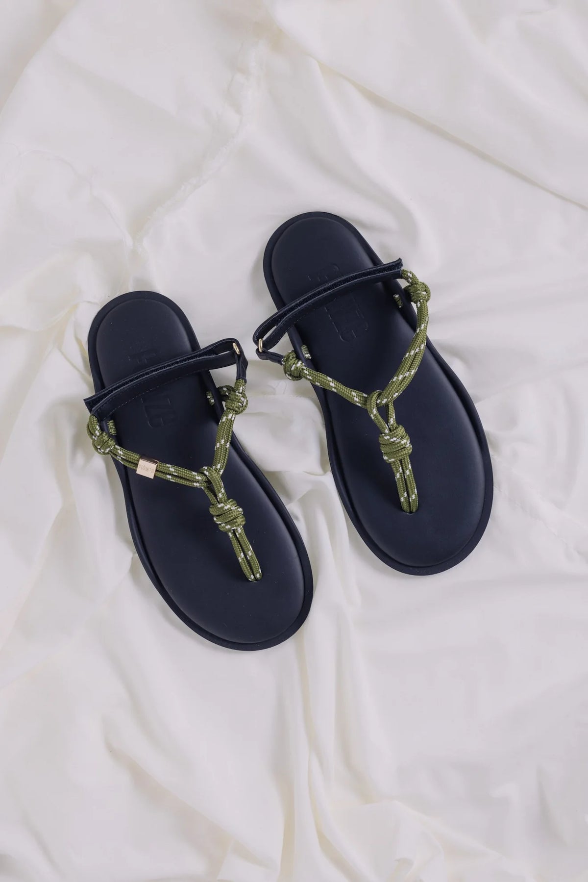 Flowze FLO military green sandals with rope straps on white fabric, available at Bungalow Furniture & Accessories.