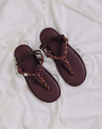 Brown knotted strap sandals by Flowze, FLO style, displayed on a soft white fabric background.