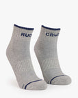 The Mother Baby Steps Ankle socks are light grey with dark blue trim and "CRU" on the cuffs. Featuring a classic tube sock look, they have reinforced toes and heels plus a textured pattern for style and comfort.