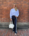 Rachel Comey Dallbey Top in a relaxed style, worn by a smiling woman next to a brick wall with a white bag.