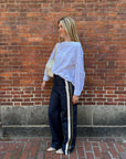 Rachel Comey Dallbey Top in a casual look, styled with navy pants and white bag against a brick wall backdrop.