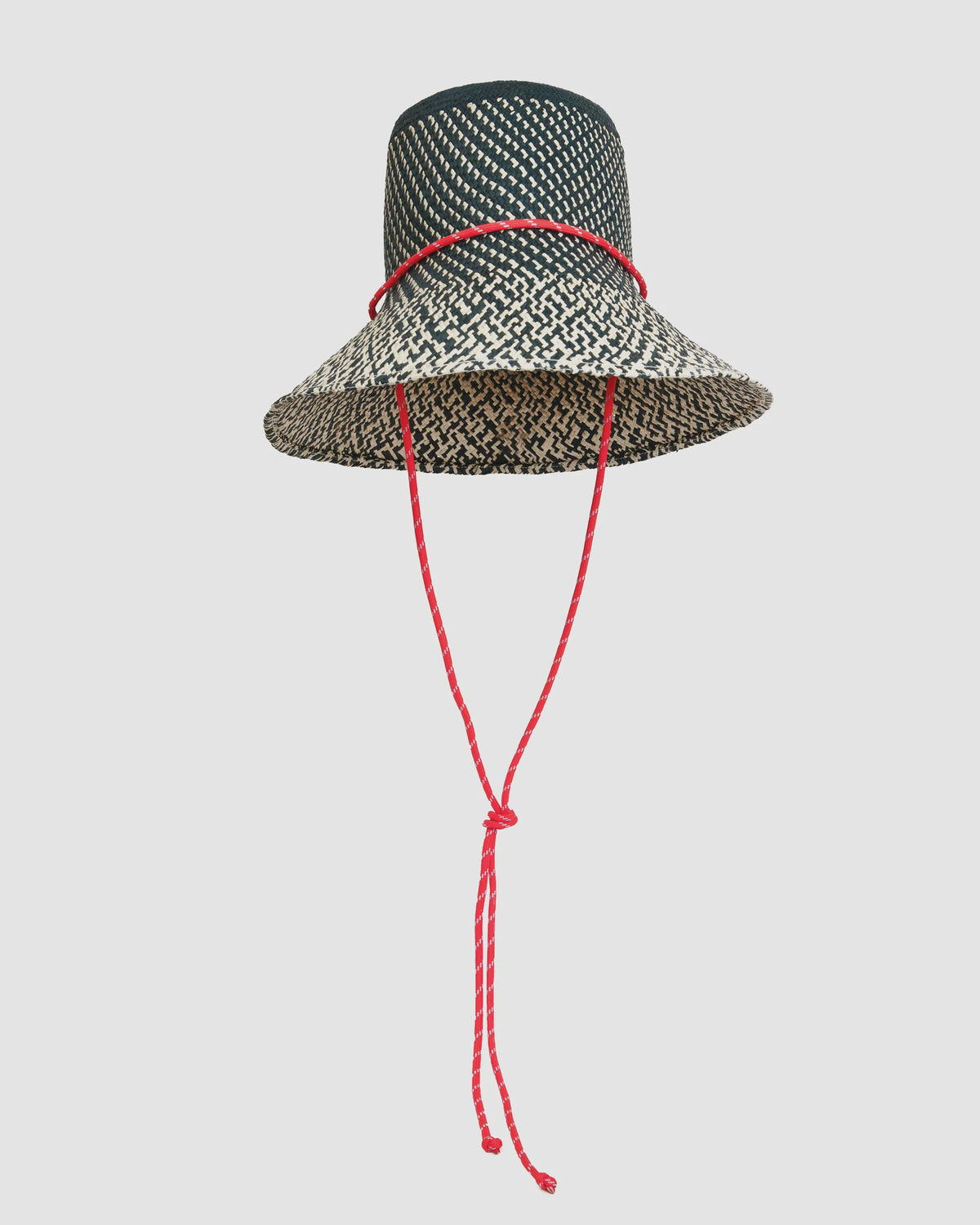 The Clare Vivier Romy Hat is a black and white woven straw rattan hat featuring a wide brim and a red sail cord strap tied in a knot, shown against a plain light background.