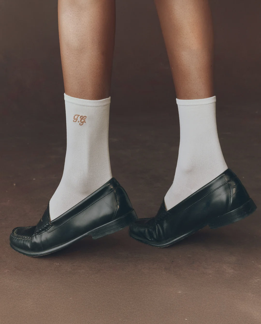 Black loafers styled with The Great Inc. Monogrammed Trouser Sock, shown standing on a brown surface.