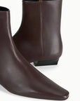 Brown lamb leather ankle boot with pointed toe and low black heel by Staud, the Wally Sock Flat style.