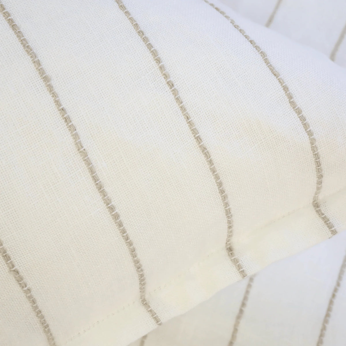 A close-up of two overlapping Blake Big Pillows 28x36 from POM POM, showcasing sophisticated stripes with vertical, thin beige lines that form a simple and elegant pattern.