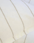 A close-up of two overlapping Blake Big Pillows 28x36 from POM POM, showcasing sophisticated stripes with vertical, thin beige lines that form a simple and elegant pattern.