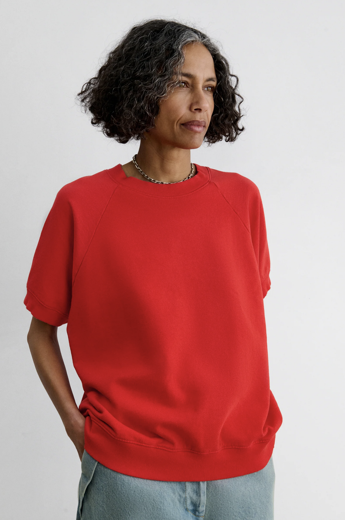 Red Rachel Comey Billi Sweatshirt paired with light blue jeans, modeled against a plain backdrop.