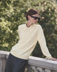 Sold Out NYC Cashmere Zip Polo in a relaxed outdoor setting, worn by woman in sunglasses by greenery and stone railing.