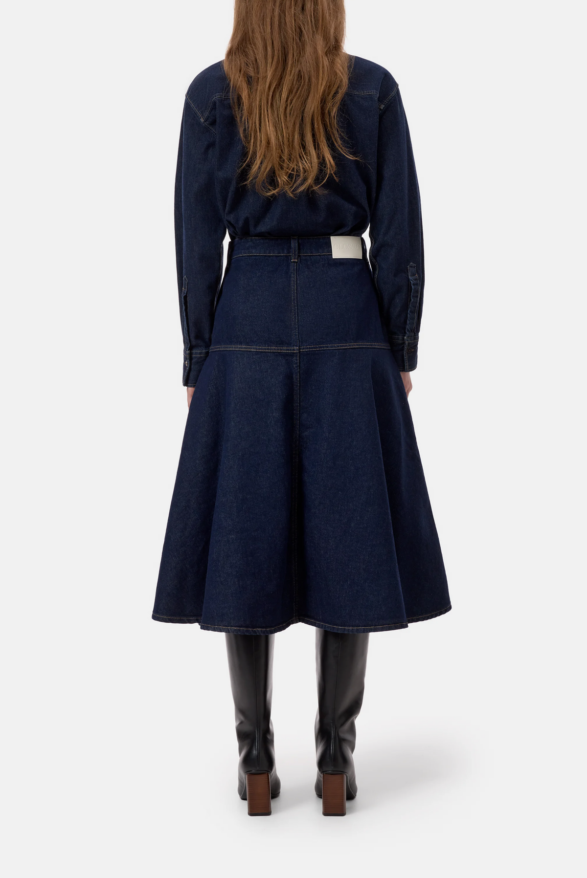 CLOSED dark blue denim midi zip skirt with an A-line flared hem, styled with black knee-high boots.