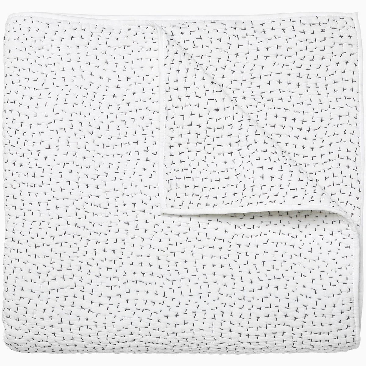 The John Robshaw Hand Stitched Coverlet Queen is made of white organic cotton with small black dashes and plus signs, shown folded to feature its reversible design.