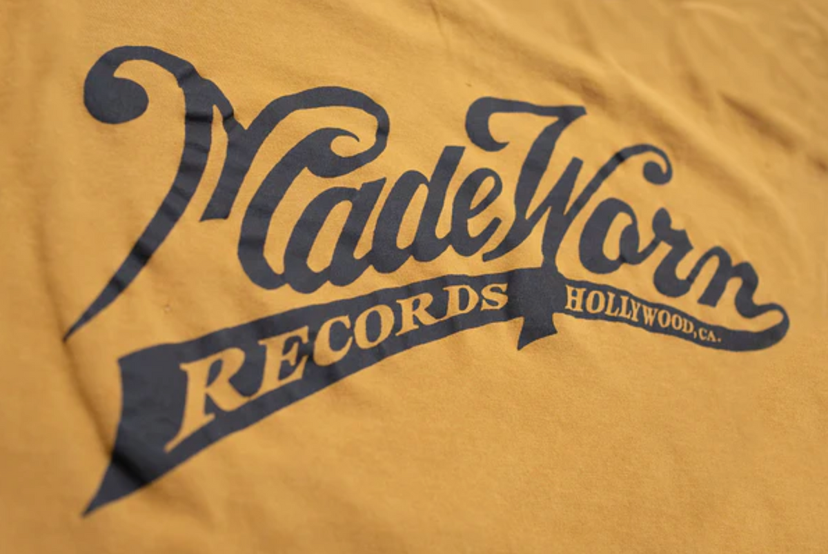 The Pocket Tee MadeWorn Records by Made Worn is a yellow vintage unisex tee made in the USA from 100% cotton, featuring "MadeWorn RECORDS HOLLYWOOD, CA." printed boldly on the pocket.