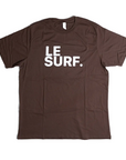 The Le Surf Tee by Ping Pong Surf Club is a brown unisex cotton t-shirt with "LE SURF." printed in bold white letters on the chest, featuring the classic Le Surf logo.