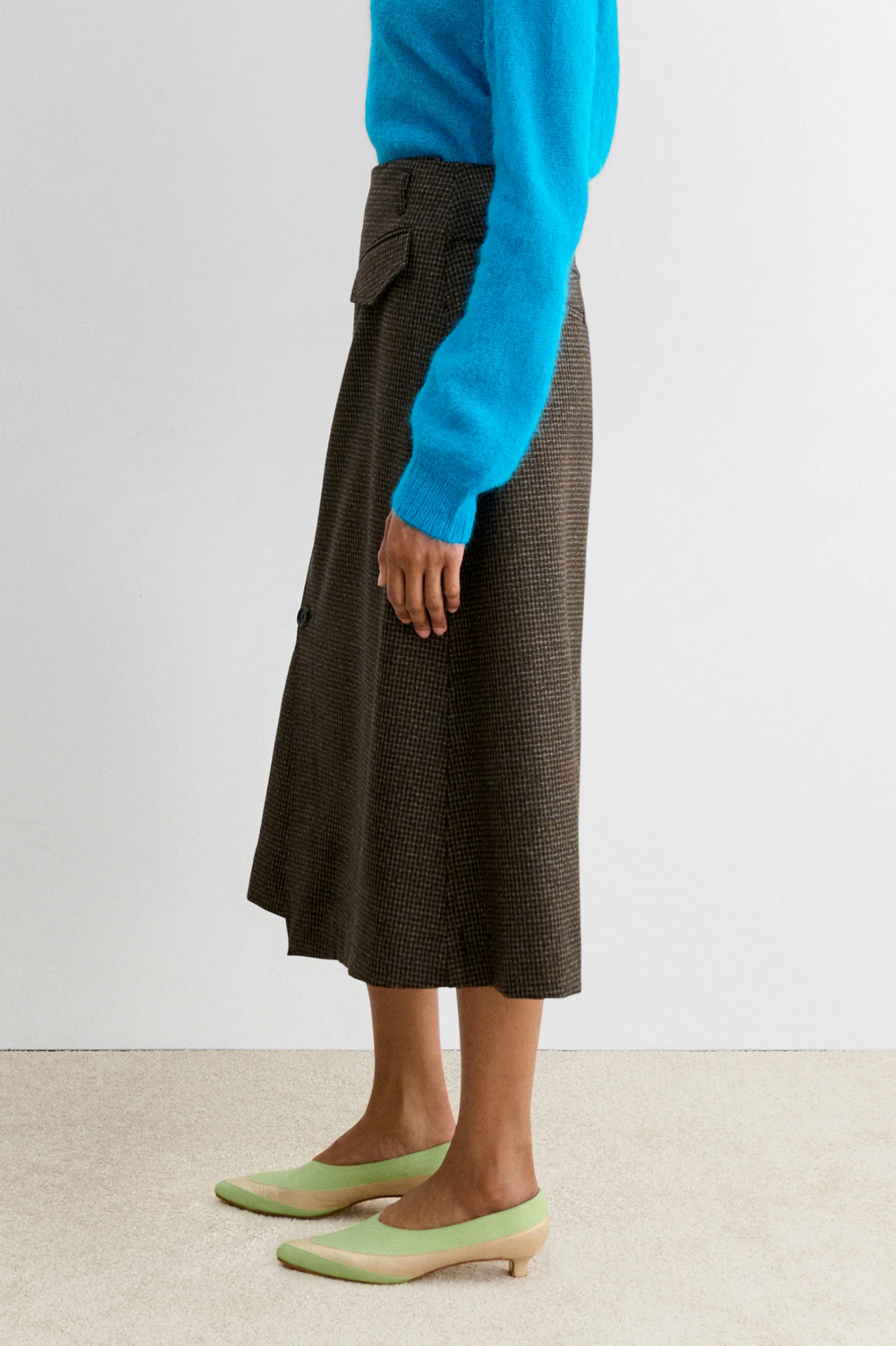 Rachel Comey Montrose Skirt styled with a blue sweater and light green heels on a beige carpet.