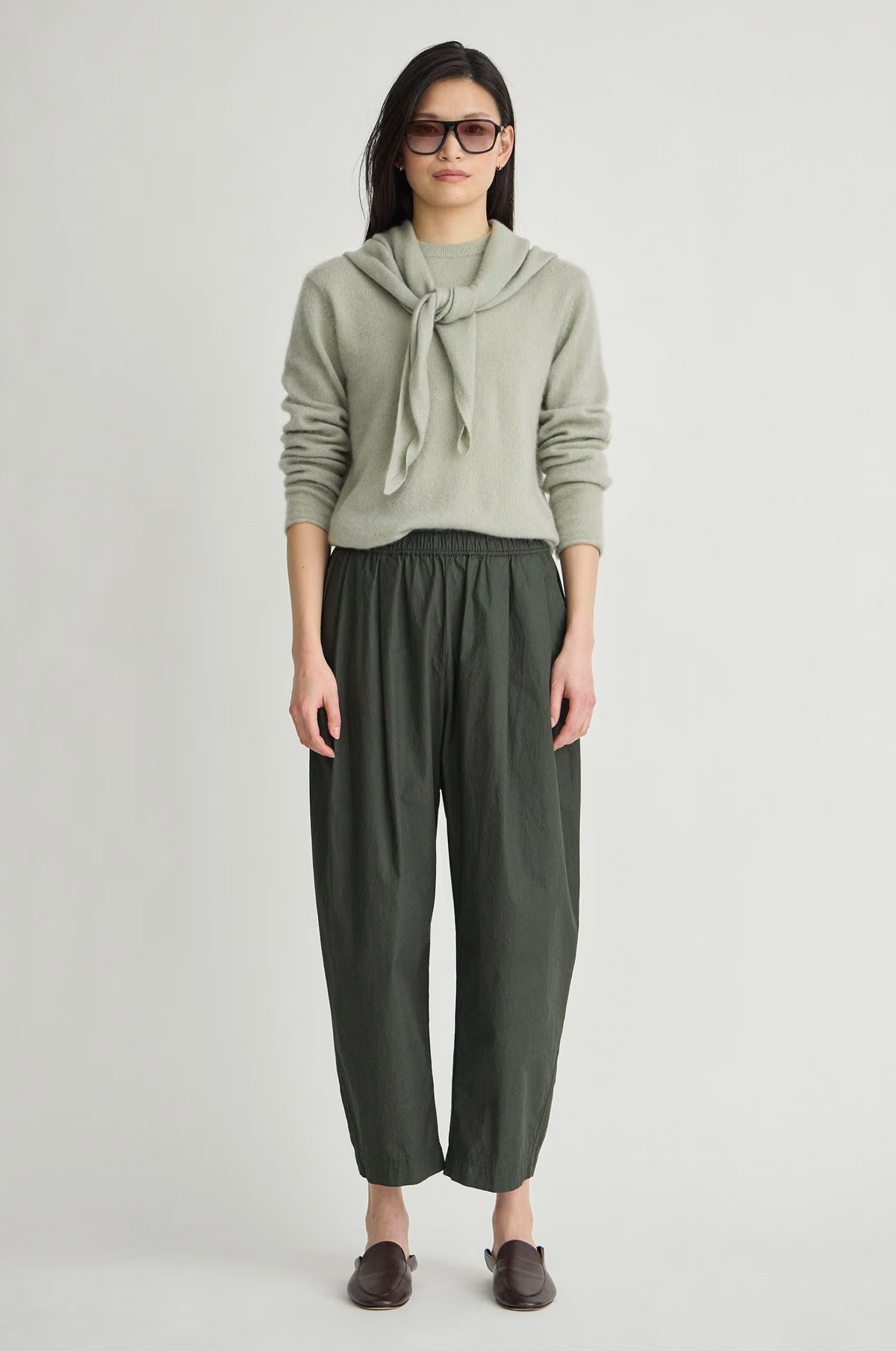 Apiece Apart Spa Pleat Pant in Rosin paired with an organic sweater, styled with brown shoes.