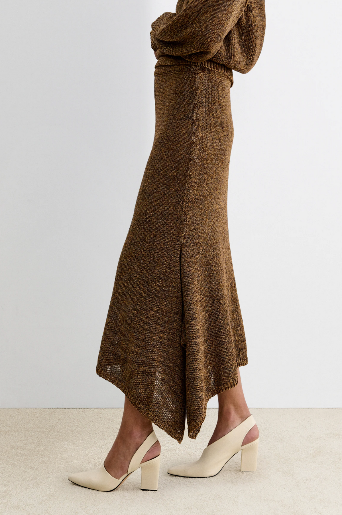 Brown knit Rachel Comey Lenco Skirt with handkerchief hem, styled with cream block-heeled shoes, side view.