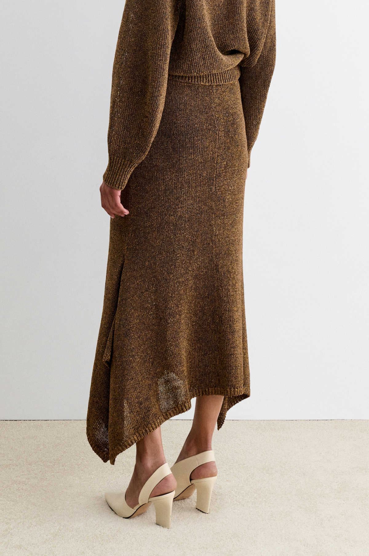 Rachel Comey Lenco Skirt styled with sweater and beige heels on a light carpet in a bright, modern room.