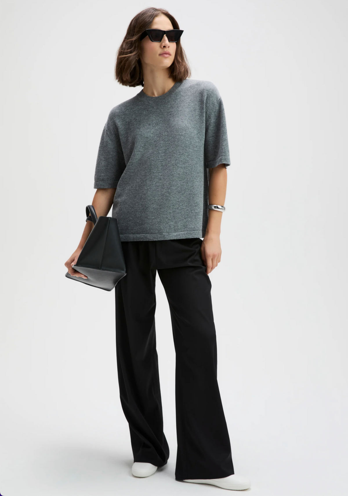 Gray cashmere oversized tee by Sold Out NYC styled with black wide-leg pants and white shoes, modern casual look.