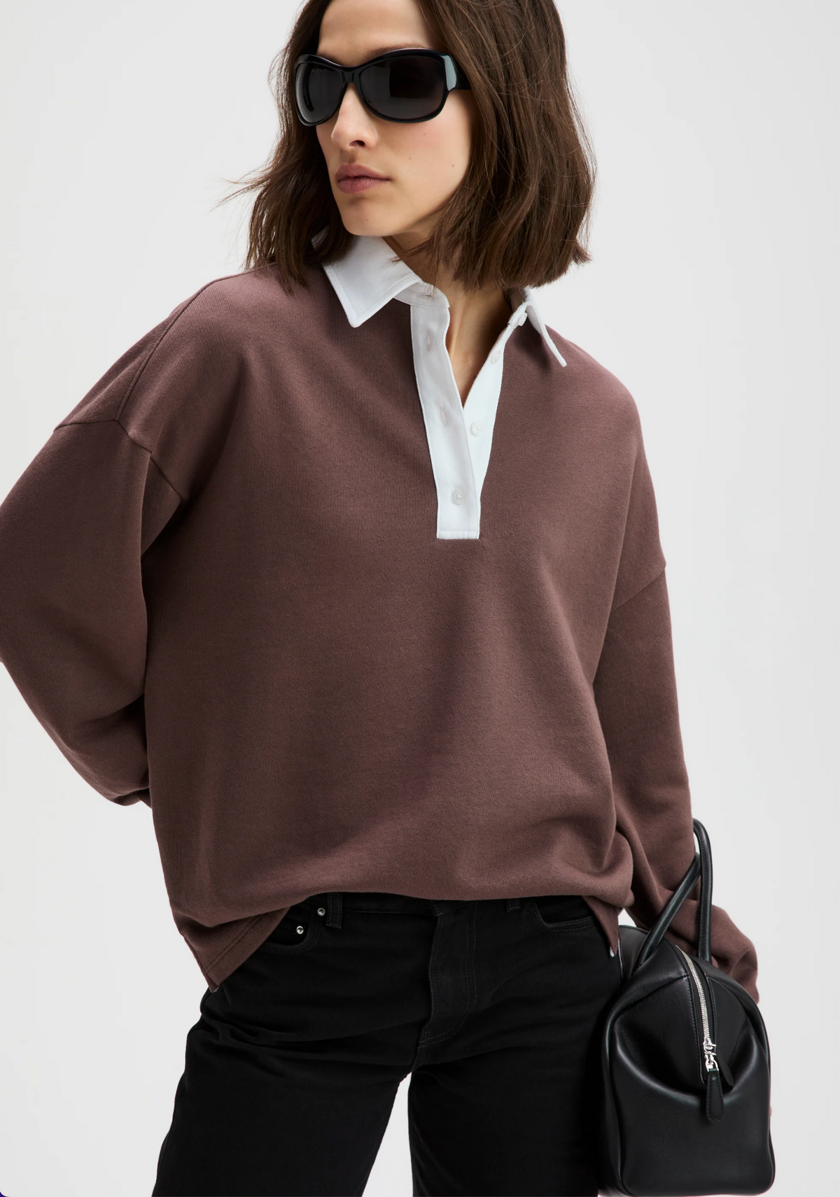 The Classic Rugby Polo by Sold Out NYC in a casual, modern style paired with black pants and a sleek handbag.