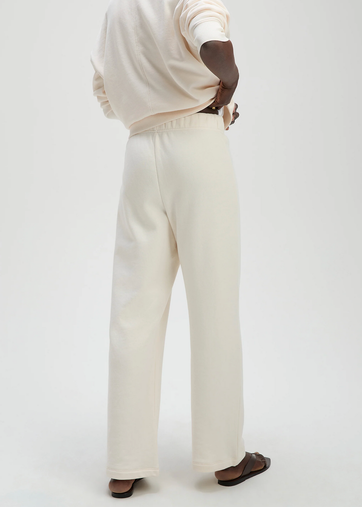 Cream Sold Out NYC sweatpant and top set, person standing hand on hip, modern casual style, neutral tone ensemble.