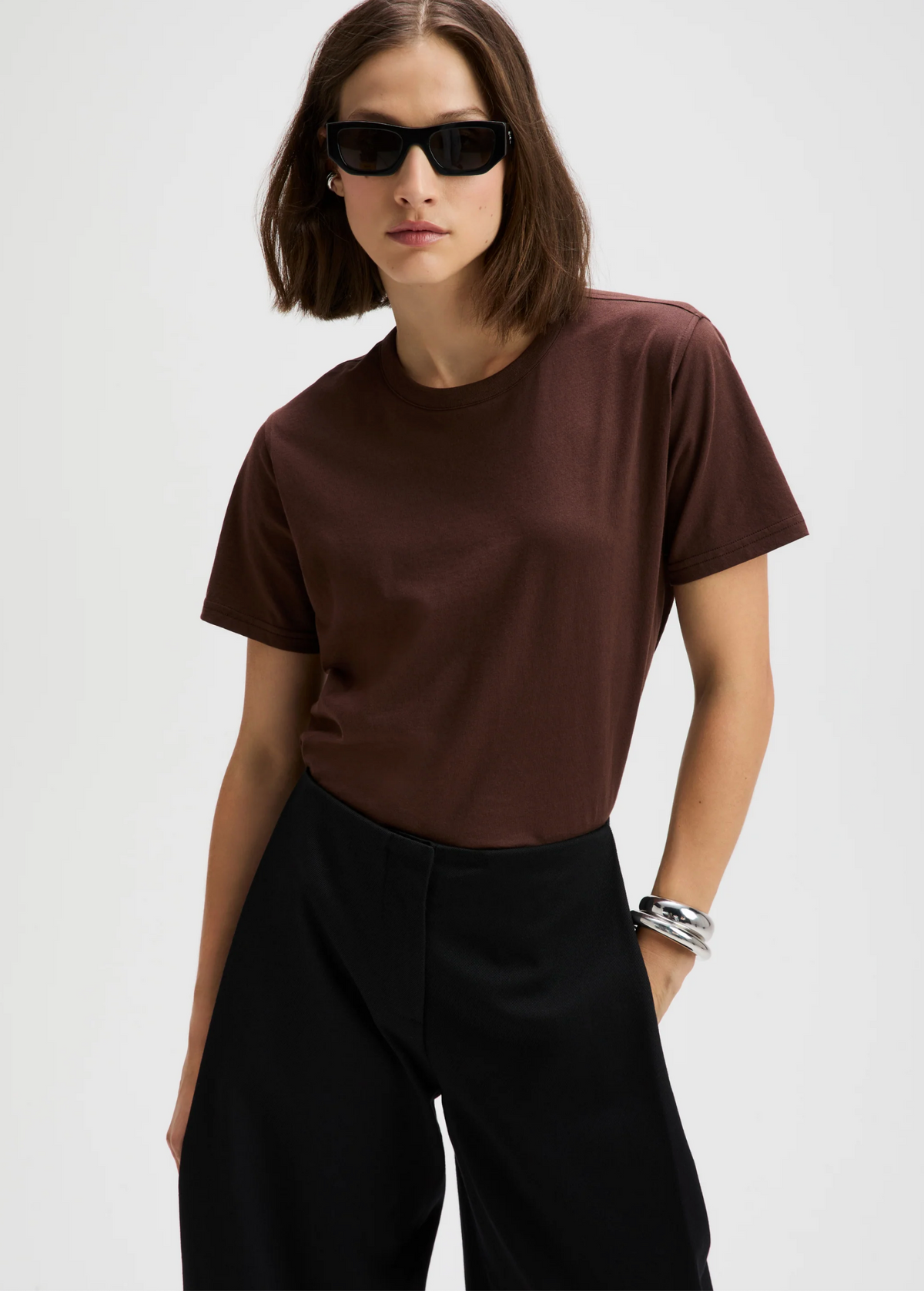 Chocolate brown Iconically Soft Perfect Tee by Sold Out NYC styled with black pants and silver bracelets.
