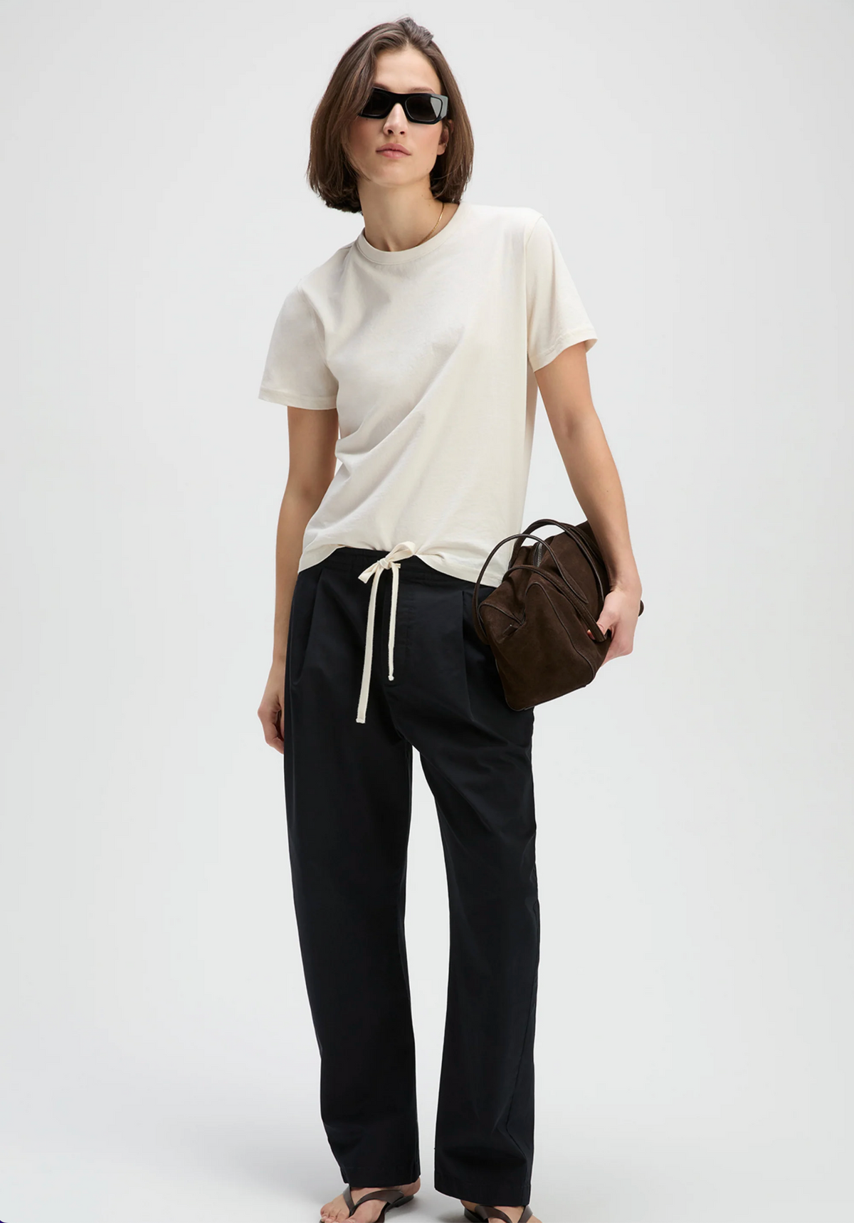 Beige Iconically Soft Perfect Tee by Sold Out NYC styled with black pants and sandals, casual street look.