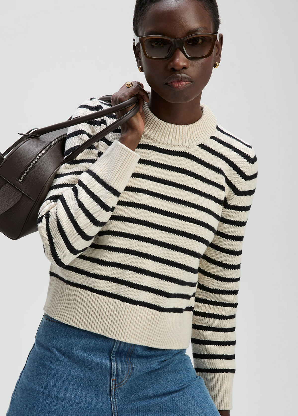 The Favorite Crew sweater by Sold Out NYC styled casually with blue jeans and a brown bag against a neutral background.