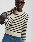 The Favorite Crew sweater by Sold Out NYC styled casually with blue jeans and a brown bag against a neutral background.