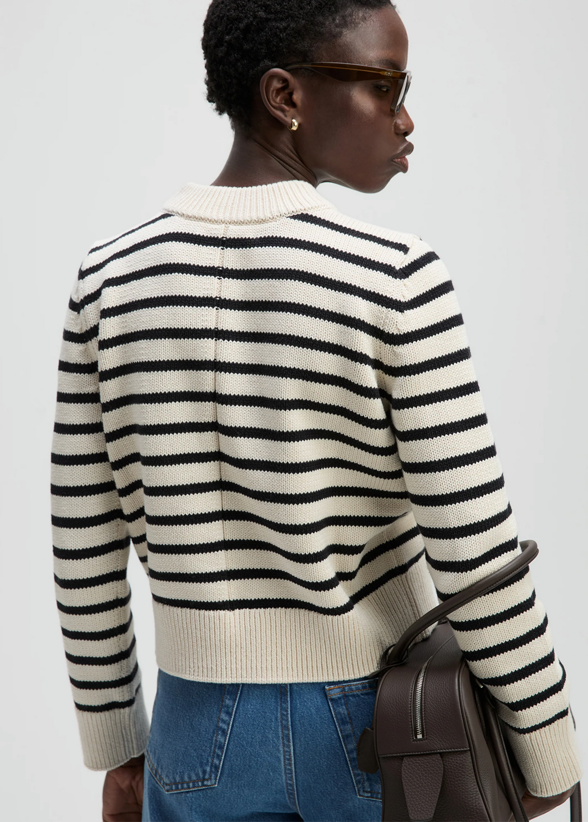 The Favorite Crew sweater and jeans by Sold Out NYC, worn casually with sunglasses and a brown bag, urban setting.