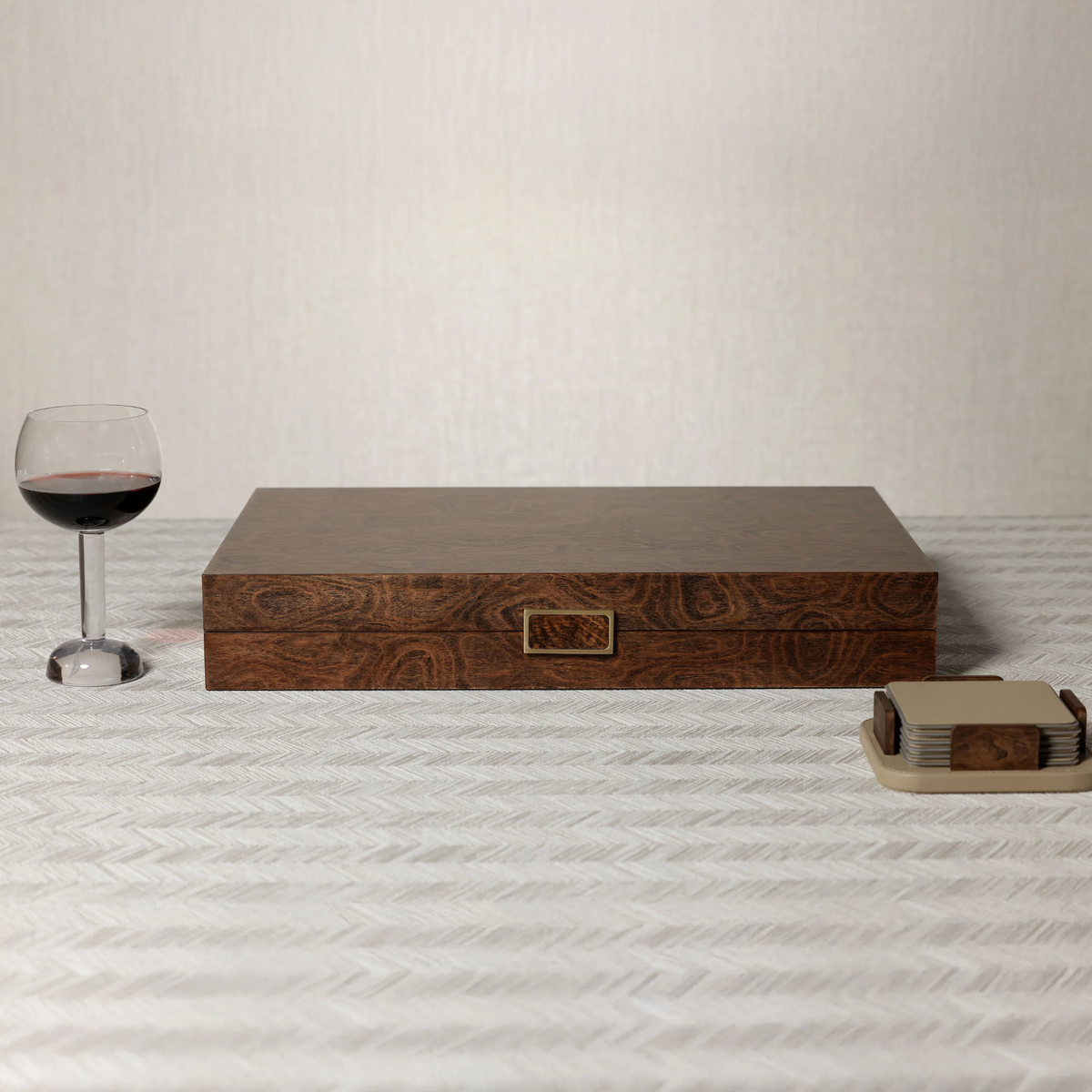 Palma de Mallorca backgammon set in closed wood veneer with metal latch, styled with red wine and coasters.