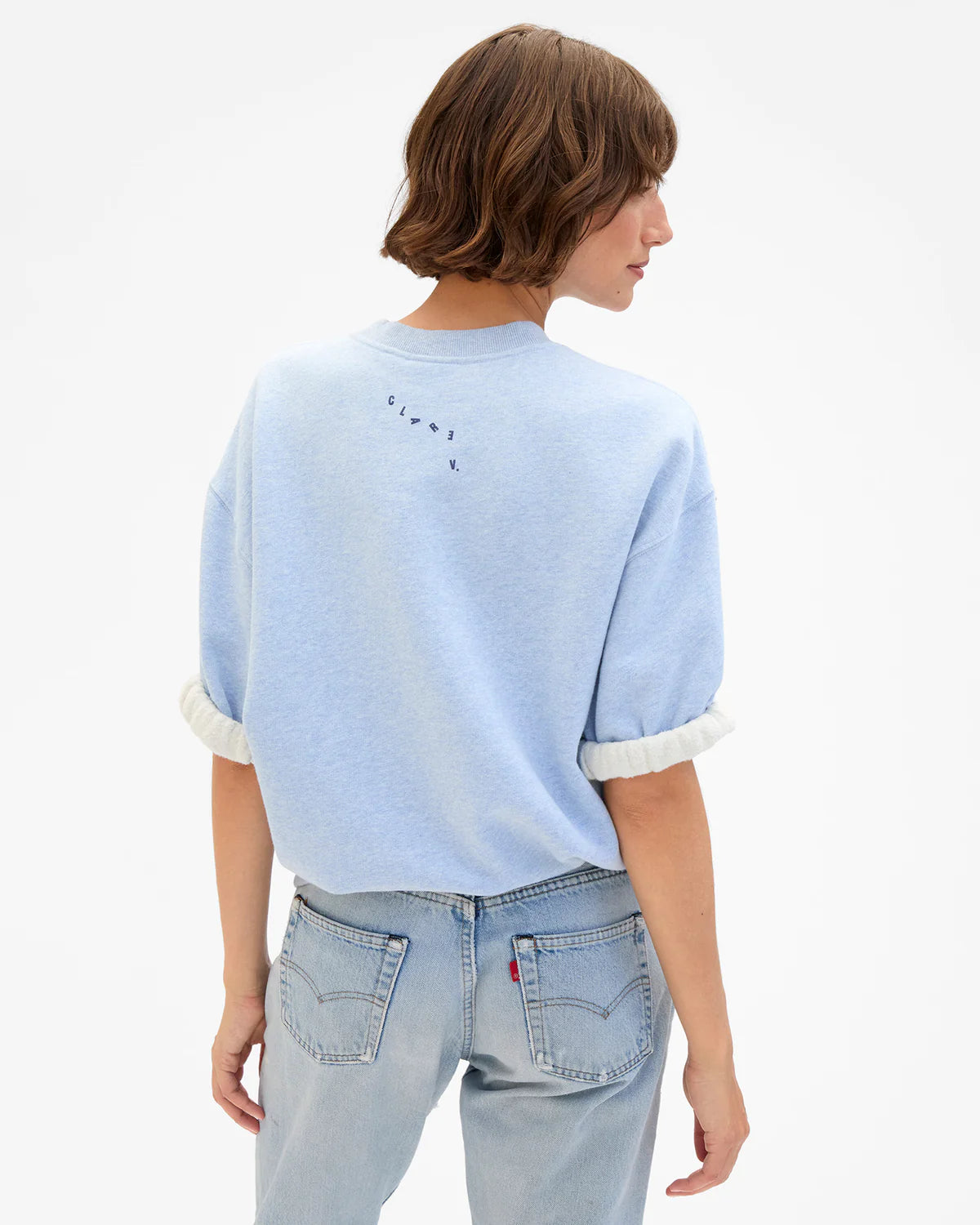 Light blue Clare Vivier SS Oversized Sweatshirt with rolled sleeves, styled casually with jeans, model facing away.
