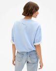 Light blue Clare Vivier SS Oversized Sweatshirt with rolled sleeves, styled casually with jeans, model facing away.