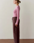 Donni The Taffeta Drawstring Cargo Pant in brown paired with a cropped pink ribbed long-sleeve shirt.
