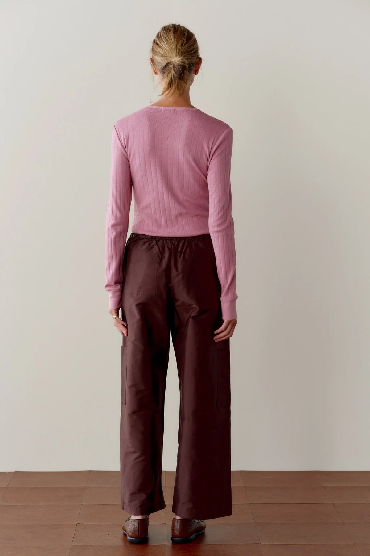 The Taffeta Drawstring Cargo Pant in dark brown worn with a pink cropped ribbed top, back view.