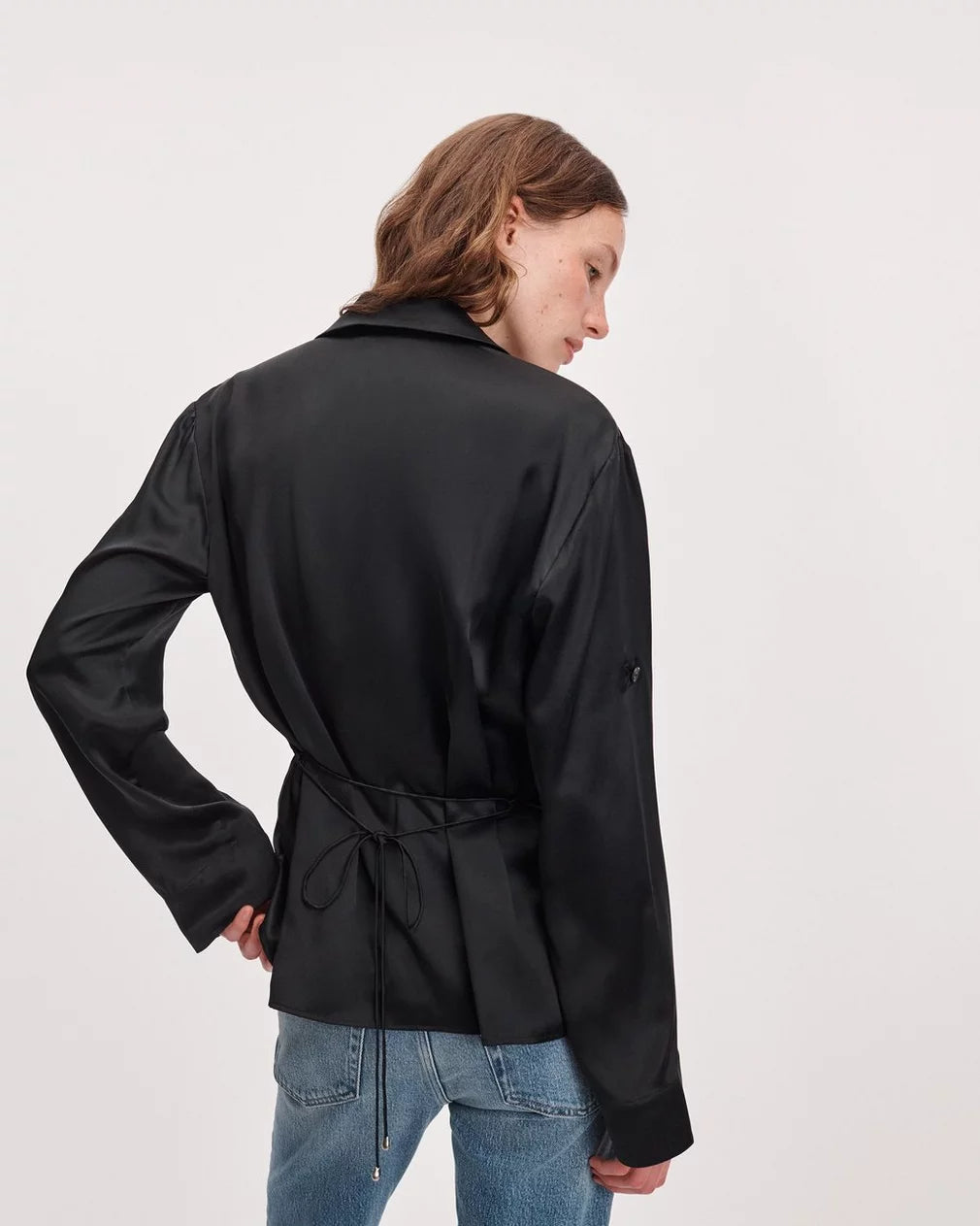 Rag & Bone sonny silk blouse paired with black satin jacket and blue jeans, model standing with hand on hip.