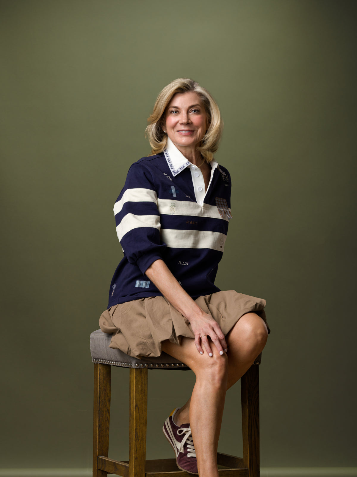 Navy striped shirt and tan skirt from Bungalow Furniture, styled casually with maroon sneakers on seated model.