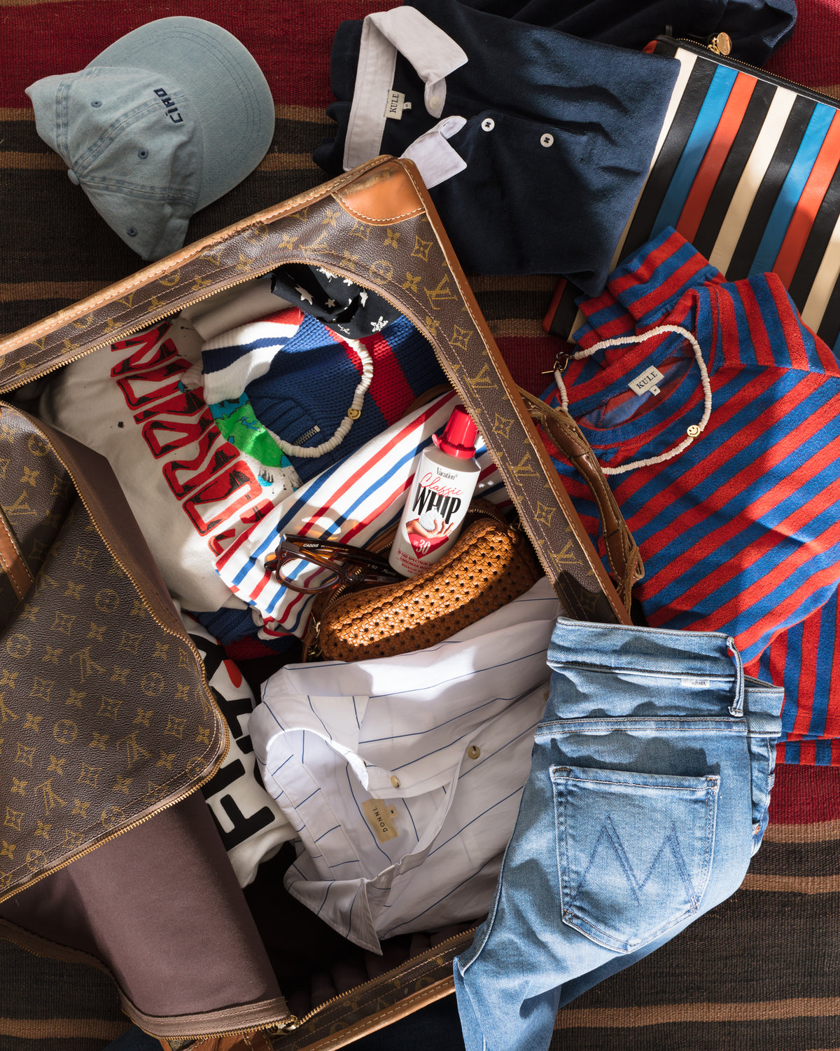 Suitcase packed with stylish vacation essentials on a patterned rug, featuring relaxed Bungalow style.