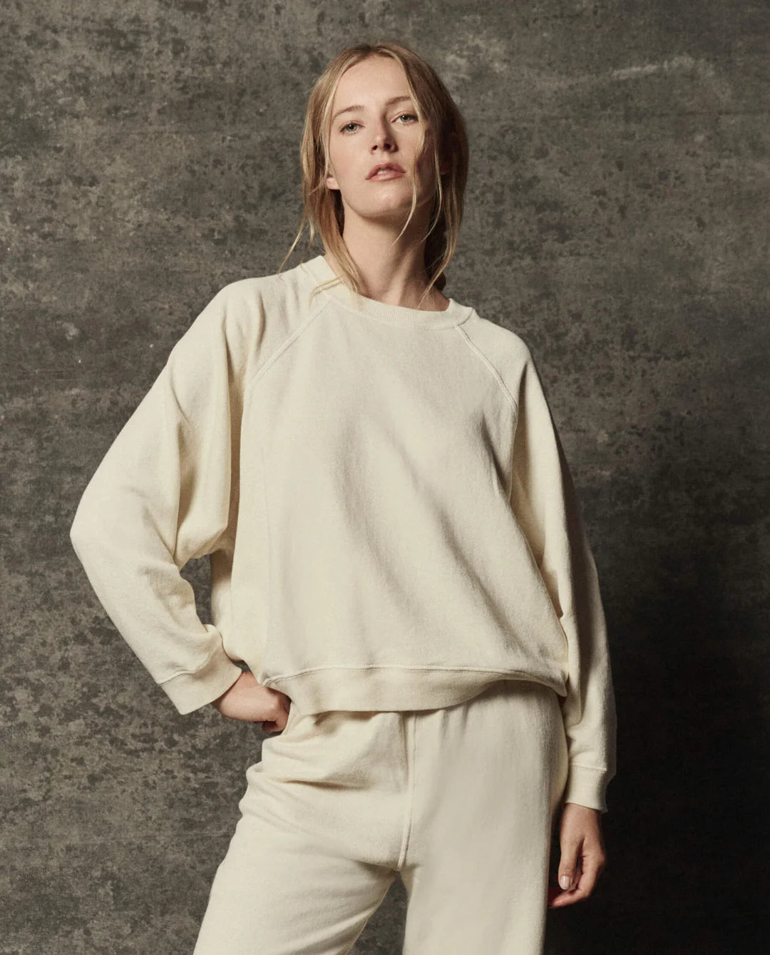 The Great Inc. Rehearsal Sweatshirt in gray, relaxed fit, modeled against a dark textured background.