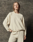 The Great Inc. Rehearsal Sweatshirt in gray, relaxed fit, modeled against a dark textured background.