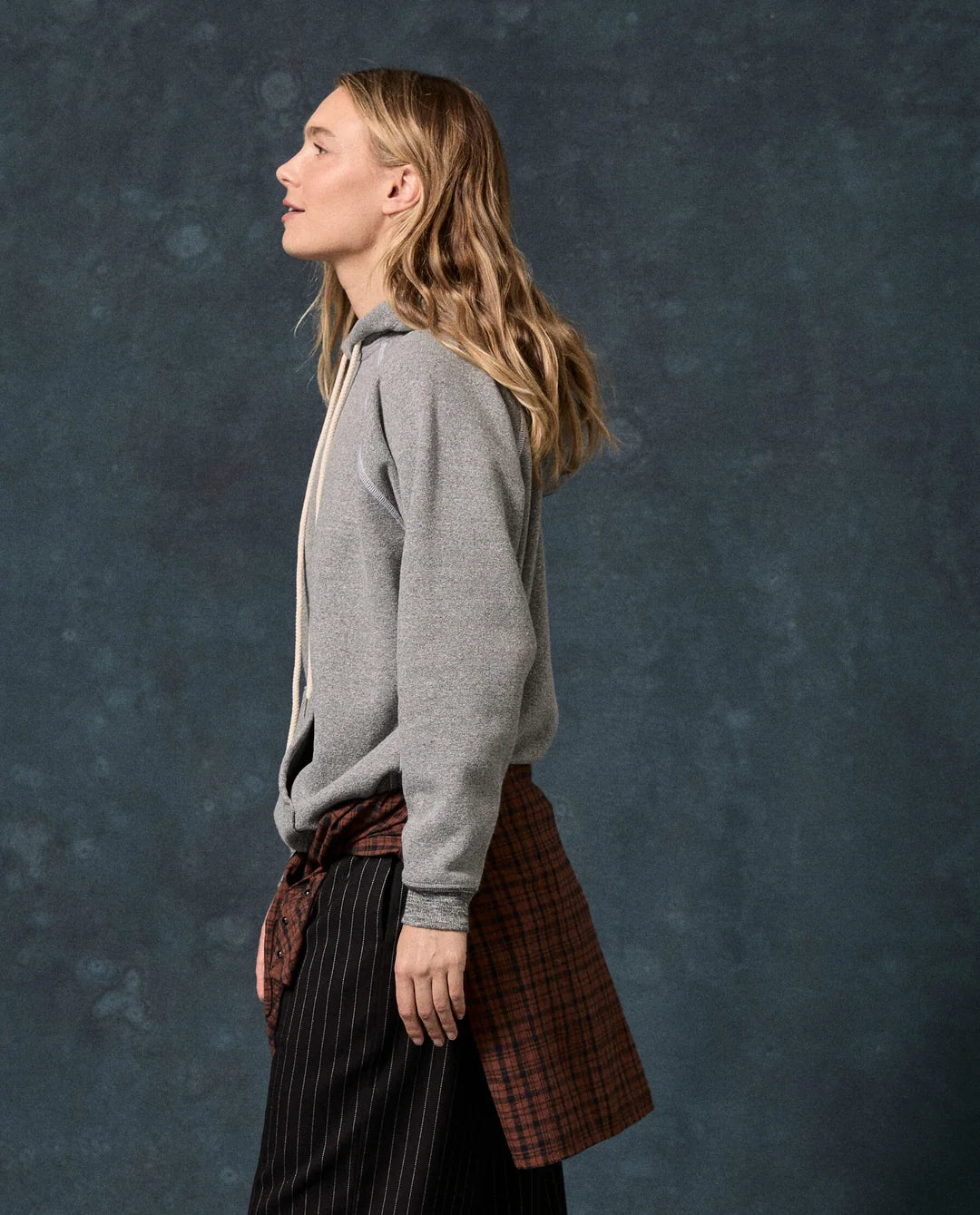 The Fleece Pullover Hoodie in grey styled with a flannel shirt and pinstriped trousers.