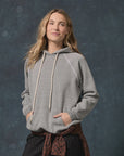 The Fleece Pullover Hoodie in vintage grey French Terry with drawstring and front pocket, worn by a woman.