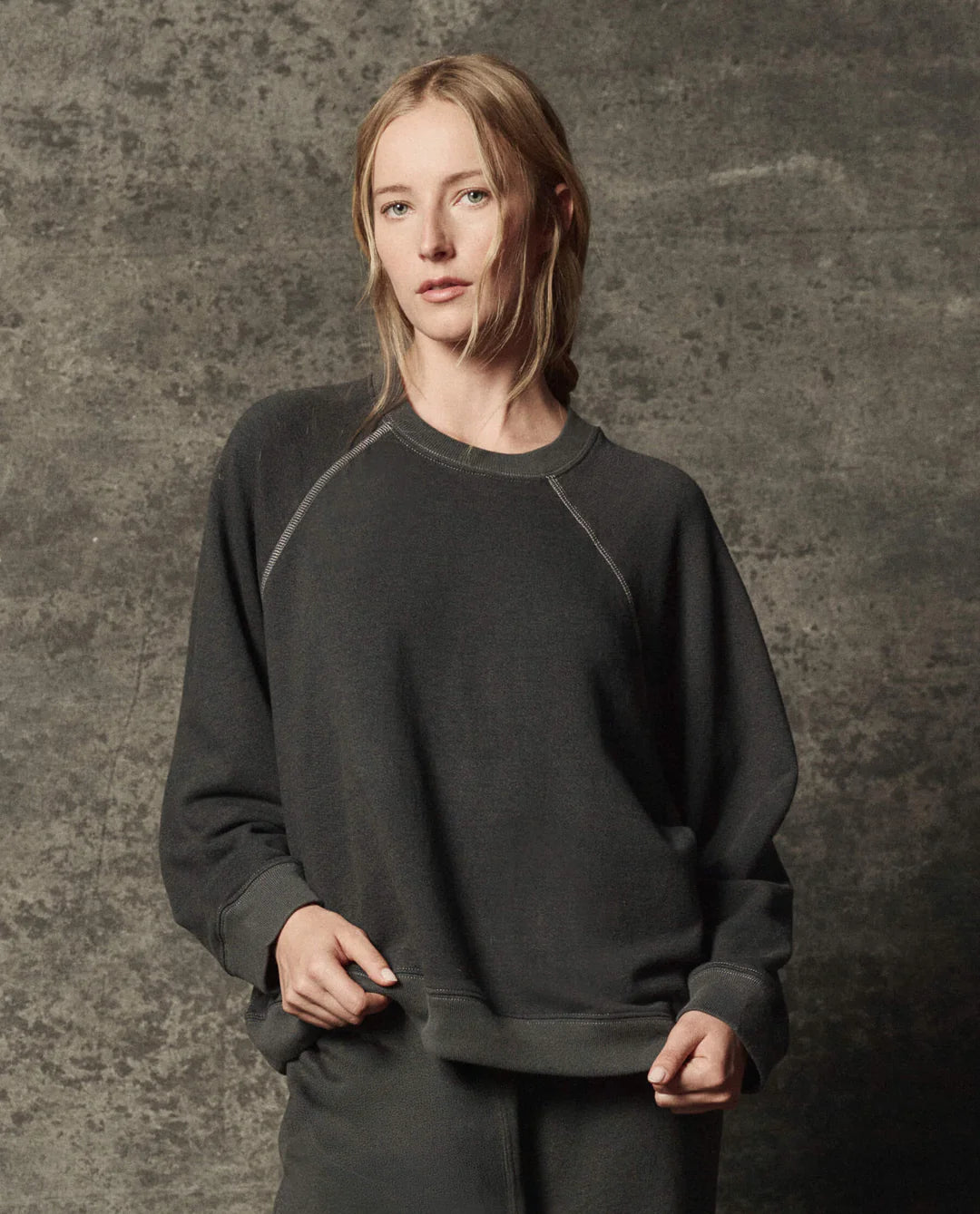 The Great Inc. Rehearsal Sweatshirt and pants in gray, relaxed fit, modeled against a textured gray backdrop.