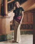 The Elastic Bias Skirt in metallic satin, worn with a black star-print t-shirt and red sash.