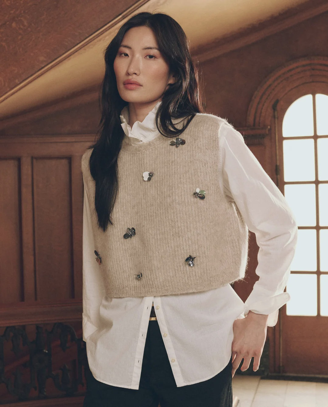 Embellished beige sweater vest with insect pins layered over a white collared shirt, Bungalow Furniture &amp; Accessories.