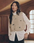 Embellished beige sweater vest with insect pins layered over a white collared shirt, Bungalow Furniture & Accessories.