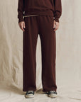The Great Inc. Lap Sweatpant in brown, styled with a matching sweatshirt and sneakers on a beige background.