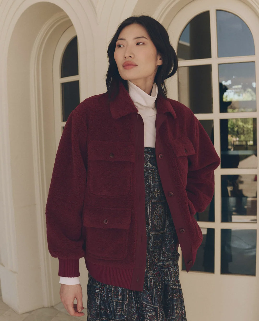 Burgundy The Great Inc. Patch Pocket Plush Jacket layered over a white turtleneck and patterned dress.